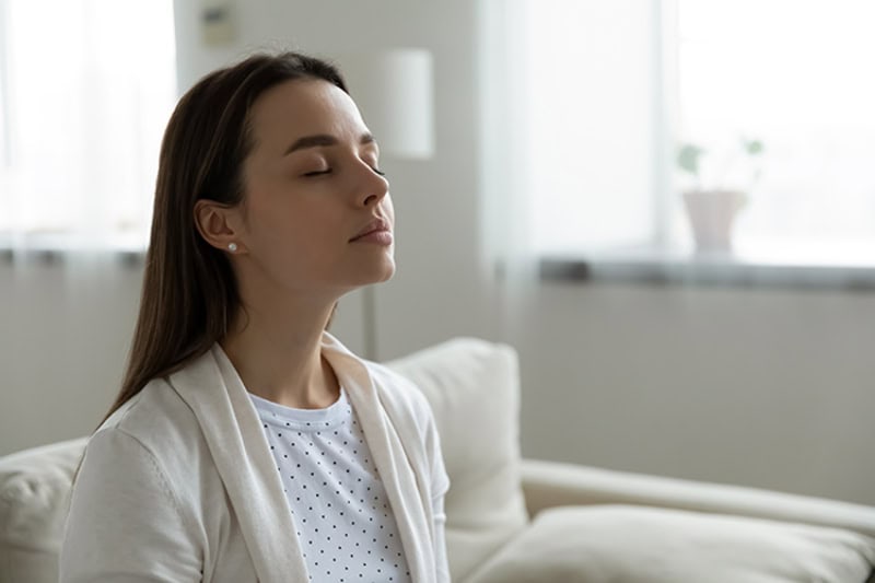 Woman in living room enjoying indoor air quality improvement.