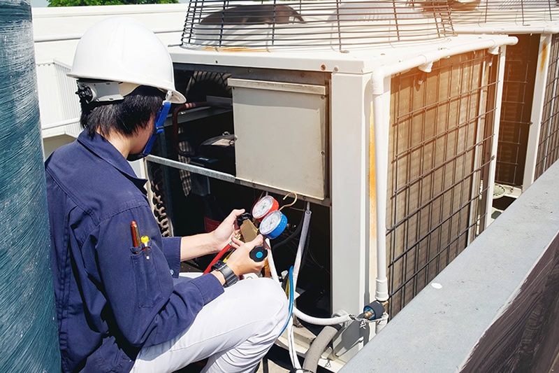 Why Is a Commercial AC Tune-Up Important? A technician fixing a commercial air conditioner.