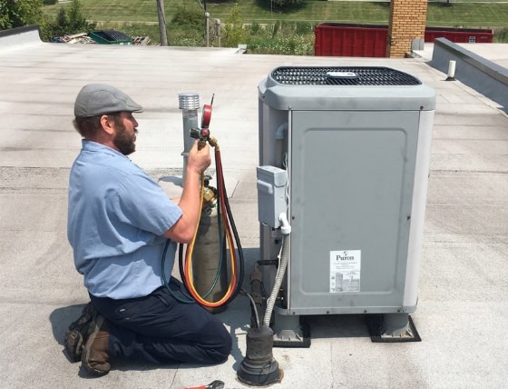 A Raymond Plumbing Heating & Air Conditioning technician performing AC Maintenance on rooftop unit.